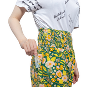 A close up shot of green and yellow floral trousers showing the access openings in the pockets for feeding tubes and catheters