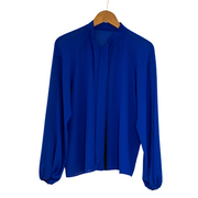 Flat lay of a royal blue chiffon pussy bow tie shirt on a hanger with the tie undone.