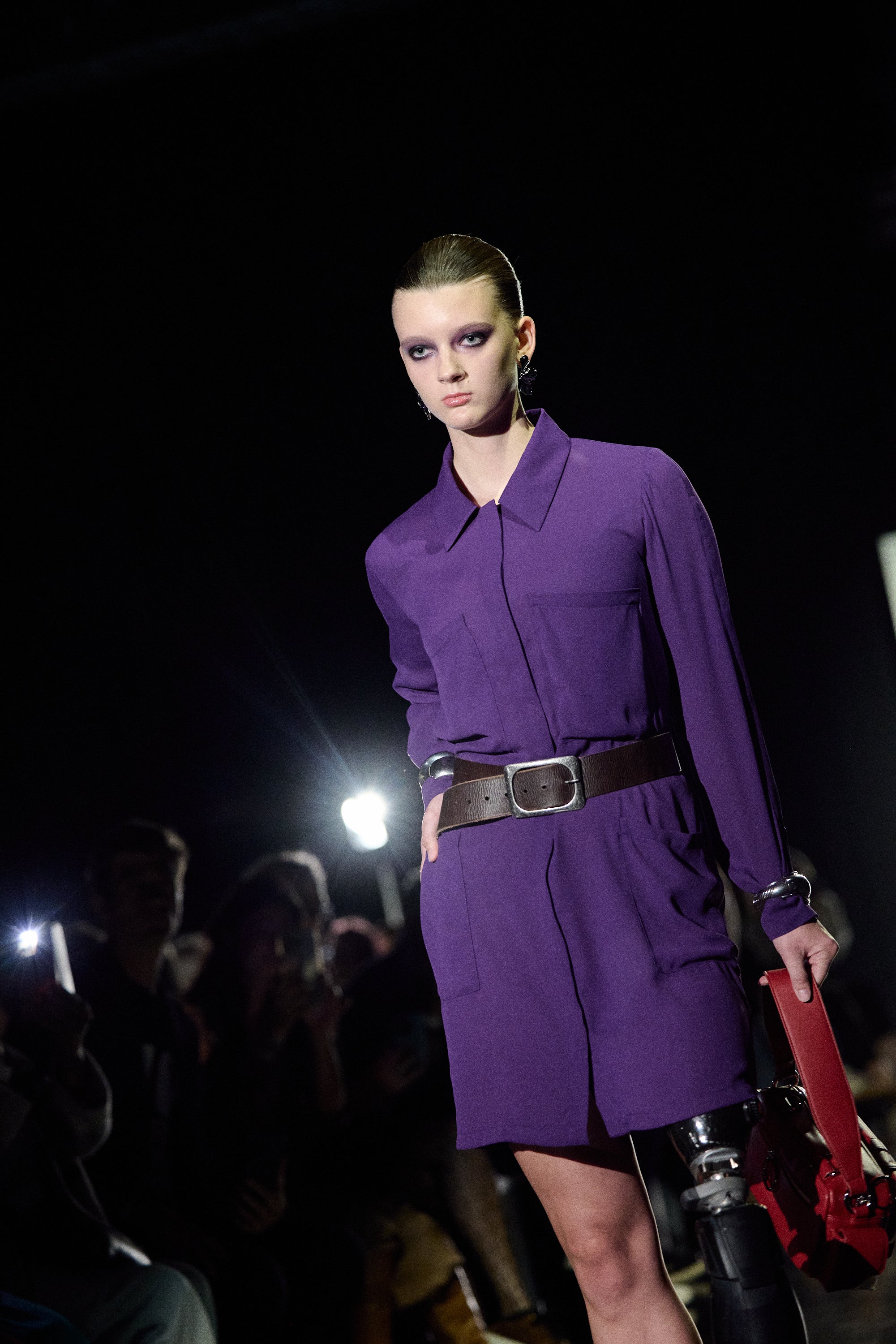 a woman in purple jumpsuit with a red bag