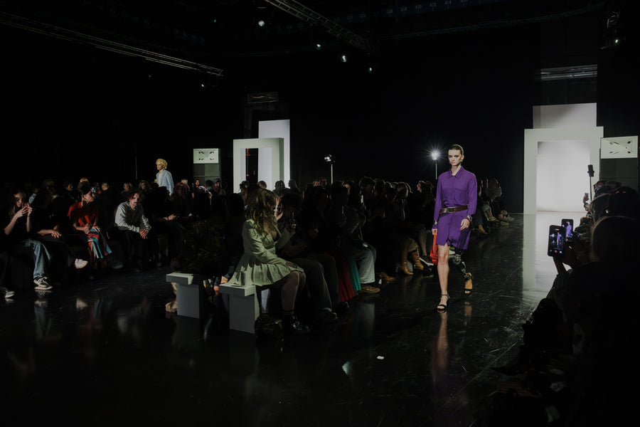 a woman walking on a runway in front of a crowd of people