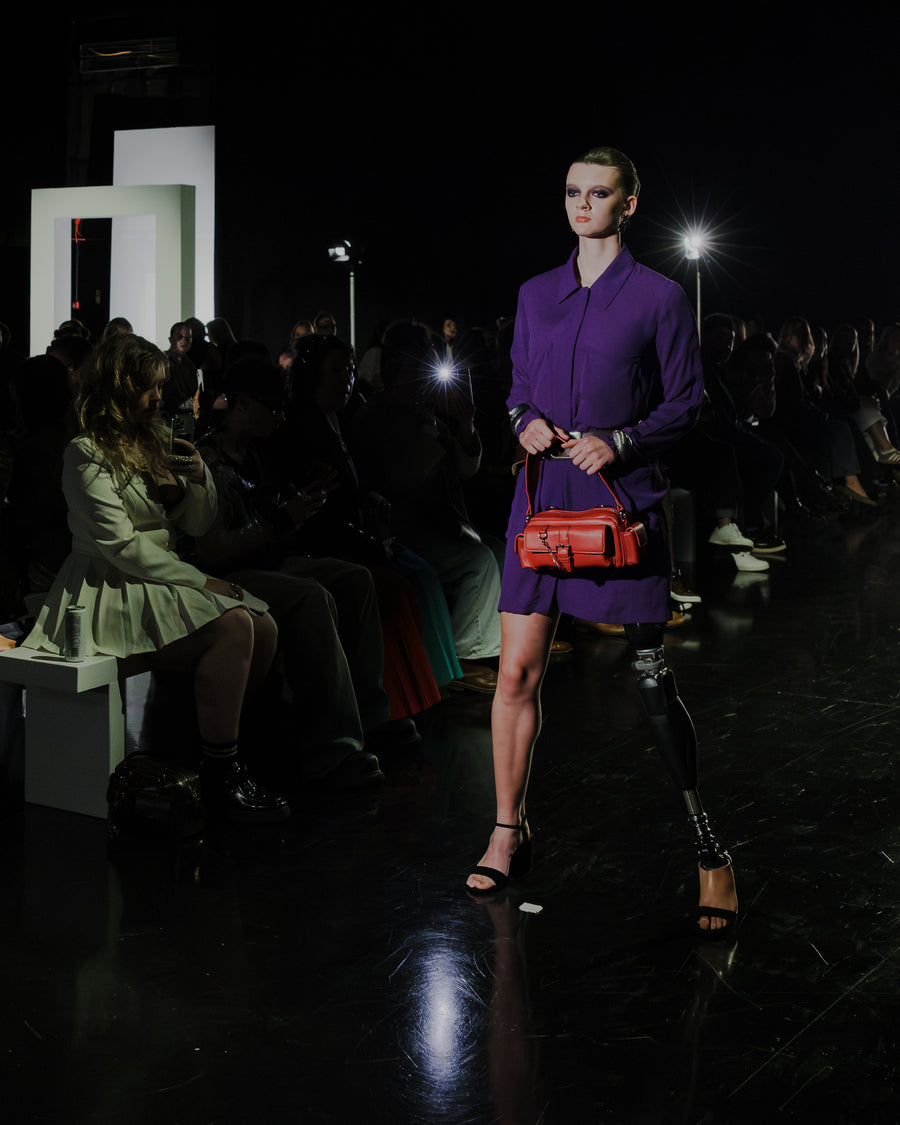 a woman in a purple dress with a red purse